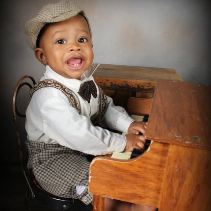 Young boy in suspenders playing a vintage piano